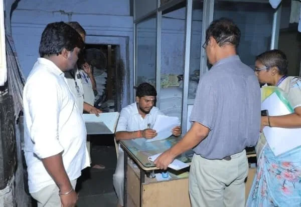 S. Ramesh stands watching as a temple official examines and signs paperwork at a desk inside the Tiruchendur temple office during the inspection